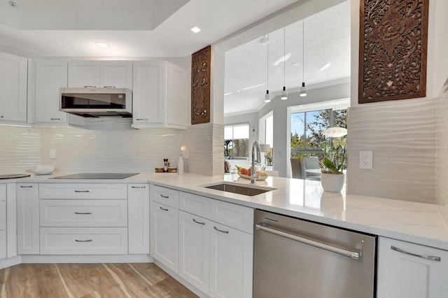 kitchen featuring appliances with stainless steel finishes, sink, white cabinets, decorative backsplash, and light stone counters