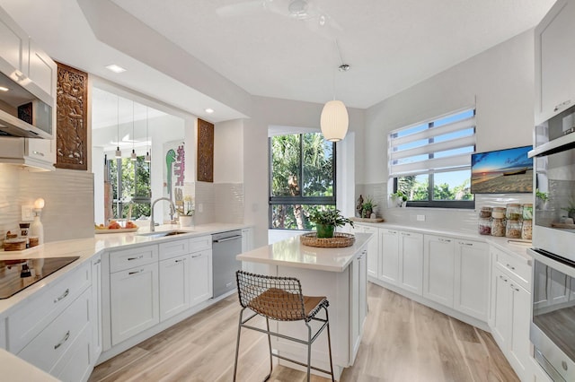 kitchen featuring white cabinetry, sink, decorative light fixtures, and appliances with stainless steel finishes