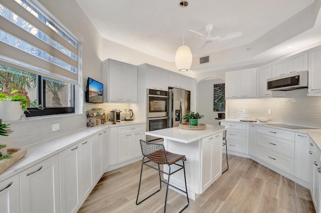 kitchen with appliances with stainless steel finishes, decorative light fixtures, a kitchen island, and white cabinets