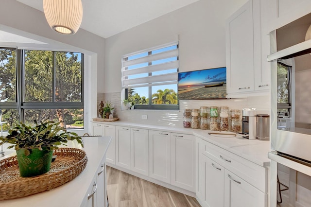 kitchen featuring white cabinets, light hardwood / wood-style floors, and decorative backsplash