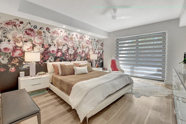 bedroom with ceiling fan, a textured ceiling, and light wood-type flooring