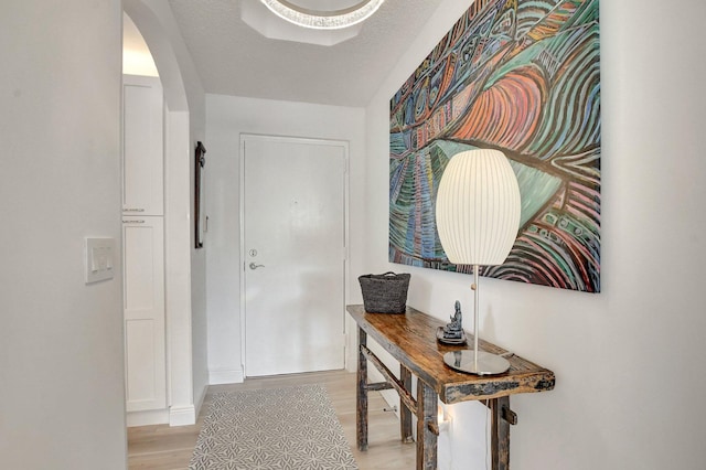 corridor with light hardwood / wood-style floors and a textured ceiling