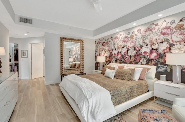 bedroom with a tray ceiling and light hardwood / wood-style flooring