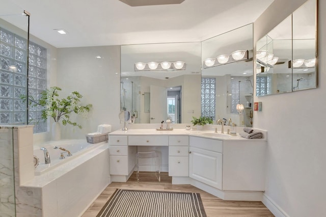 bathroom with independent shower and bath, vanity, and hardwood / wood-style floors