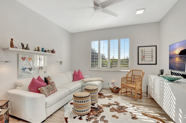 living room featuring ceiling fan, a textured ceiling, and light wood-type flooring