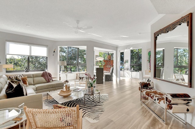 living room featuring crown molding, vaulted ceiling, light hardwood / wood-style flooring, a textured ceiling, and ceiling fan