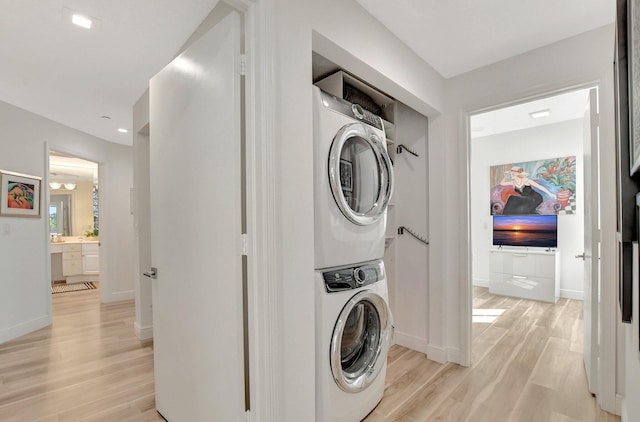 clothes washing area featuring stacked washer / drying machine and light hardwood / wood-style flooring