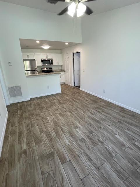 kitchen featuring white cabinets, dark hardwood / wood-style flooring, ceiling fan, kitchen peninsula, and stainless steel appliances