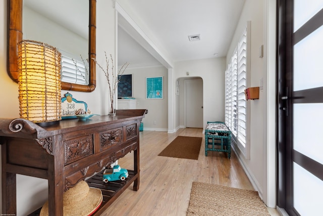 foyer entrance with ornamental molding and light wood-type flooring