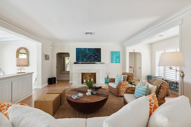 living room featuring a premium fireplace, ornamental molding, and light hardwood / wood-style floors