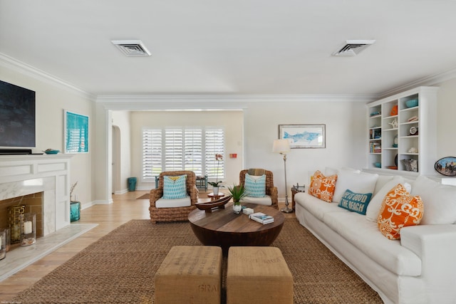 living room with ornamental molding, a high end fireplace, and light hardwood / wood-style flooring