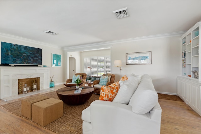 living room featuring light hardwood / wood-style flooring, ornamental molding, and a premium fireplace