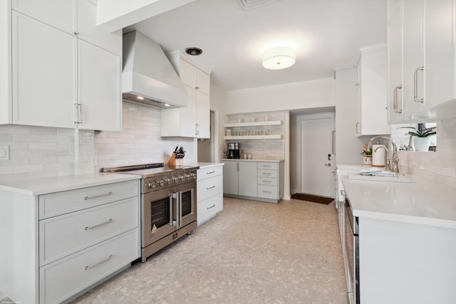 kitchen featuring high end stainless steel range oven, white cabinetry, decorative backsplash, and custom exhaust hood