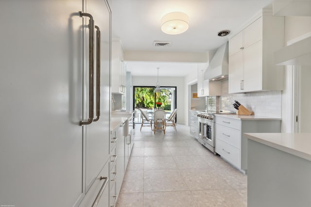 kitchen featuring white cabinetry, high quality appliances, tasteful backsplash, decorative light fixtures, and wall chimney exhaust hood