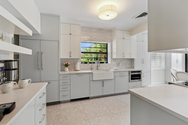 kitchen with sink, decorative backsplash, oven, and white cabinets