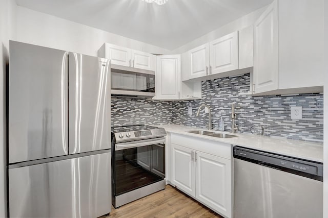 kitchen with sink, light hardwood / wood-style flooring, stainless steel appliances, tasteful backsplash, and white cabinets