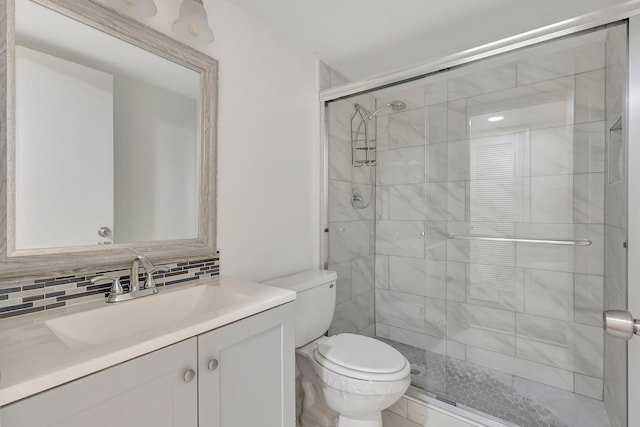 bathroom with tasteful backsplash, vanity, toilet, and an enclosed shower