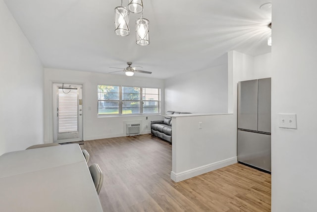 unfurnished living room with a wall mounted air conditioner, light hardwood / wood-style flooring, and ceiling fan