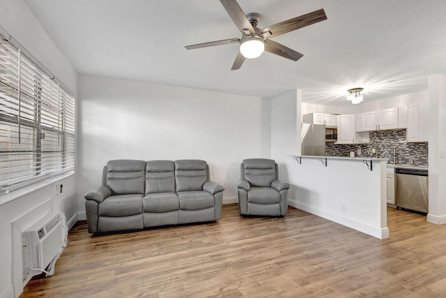 living room with ceiling fan, an AC wall unit, and light wood-type flooring