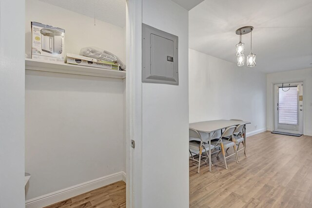 dining area featuring an inviting chandelier, electric panel, and light hardwood / wood-style flooring