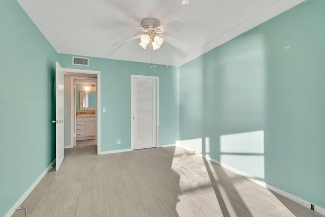 unfurnished bedroom featuring wood finished floors, a ceiling fan, visible vents, baseboards, and a closet