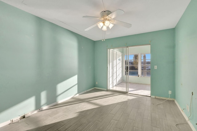 empty room with ceiling fan, baseboards, and wood finish floors