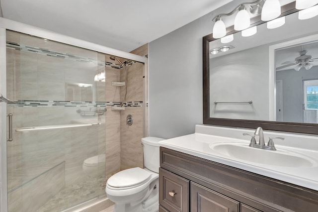 bathroom featuring vanity, a shower stall, toilet, and a ceiling fan