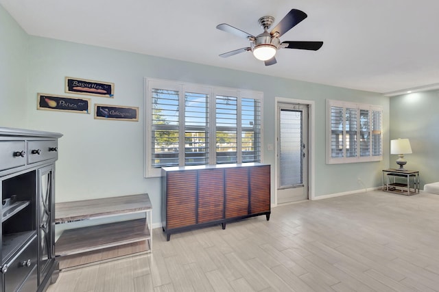 interior space with baseboards, ceiling fan, and light wood finished floors