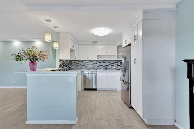 kitchen with stainless steel appliances, a peninsula, white cabinets, light countertops, and tasteful backsplash