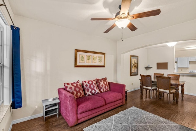 living room featuring ceiling fan, baseboards, and wood finished floors