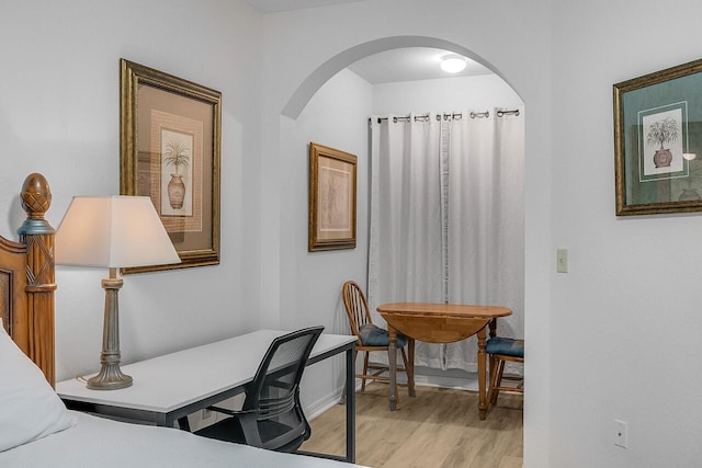 office space with arched walkways, light wood finished floors, and baseboards