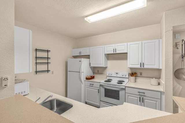 kitchen with gray cabinets, white appliances, a textured ceiling, white cabinetry, and a sink