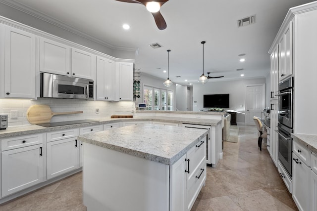 kitchen with decorative light fixtures, a kitchen island, white cabinets, ceiling fan, and backsplash