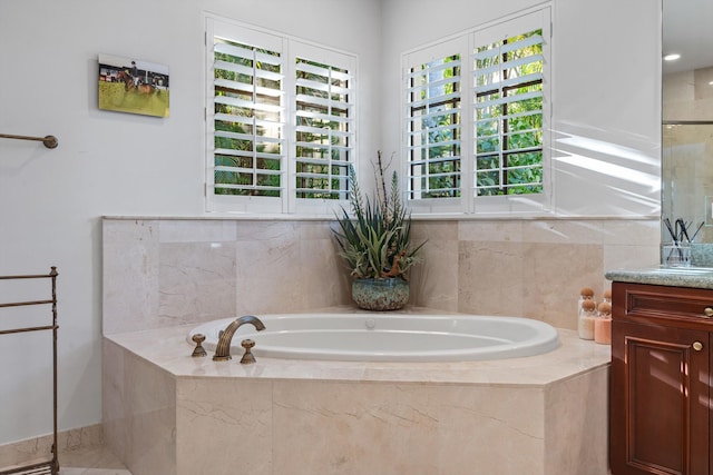 bathroom with tiled tub and vanity