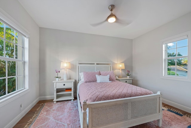 bedroom with hardwood / wood-style flooring, ceiling fan, and multiple windows