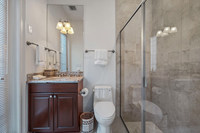 bathroom featuring vanity, a shower with shower door, and toilet