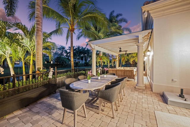 patio terrace at dusk featuring a pergola and ceiling fan