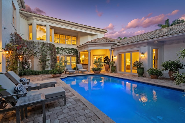 back house at dusk featuring a patio