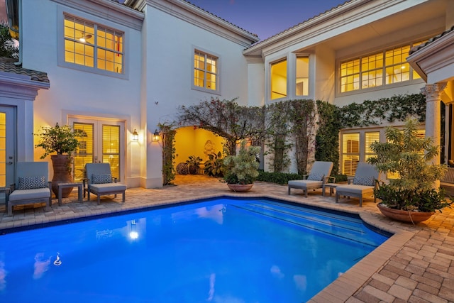 pool at dusk featuring a patio