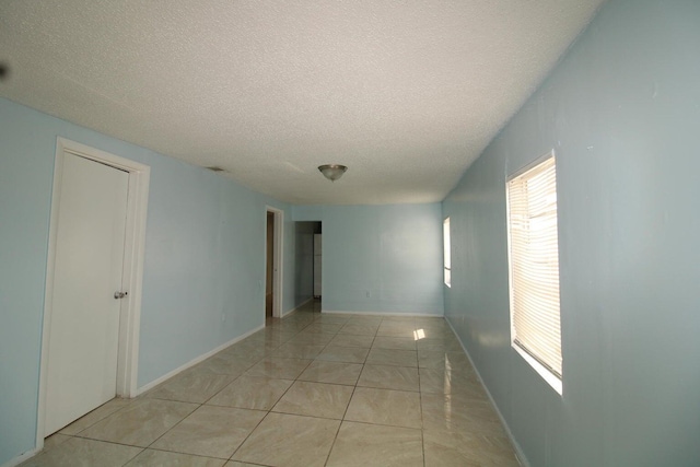 unfurnished room with light tile patterned floors and a textured ceiling