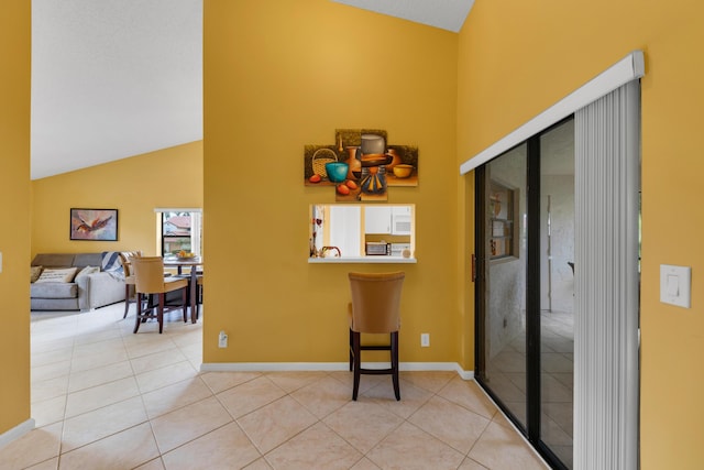 hallway featuring light tile patterned flooring and high vaulted ceiling