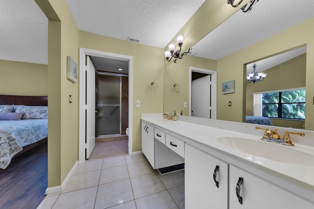 bathroom featuring a chandelier, tile patterned flooring, vanity, toilet, and a textured ceiling