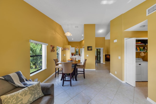 dining area featuring washer / clothes dryer, light tile patterned floors, and high vaulted ceiling