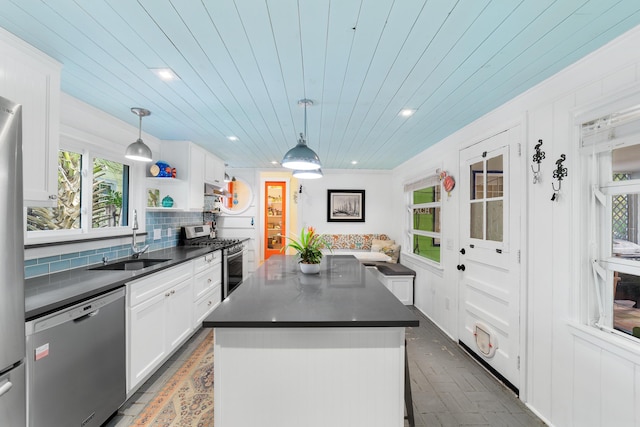 kitchen with white cabinetry, decorative light fixtures, a center island, and appliances with stainless steel finishes