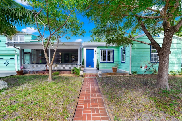 view of front of home with a front lawn, a garage, and a sunroom