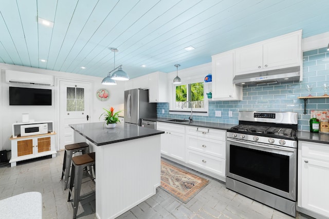 kitchen with sink, decorative light fixtures, a wall mounted AC, a center island, and appliances with stainless steel finishes