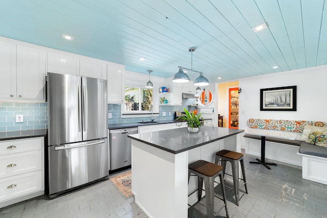 kitchen with a breakfast bar area, stainless steel appliances, a center island, and white cabinets