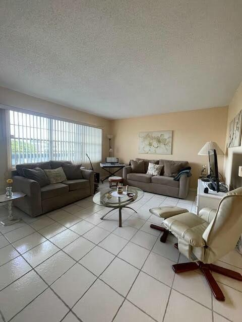 living room with light tile patterned flooring, a textured ceiling, and a wealth of natural light