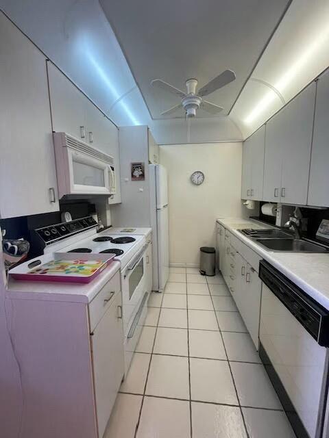 kitchen with white cabinetry, washer / dryer, sink, ceiling fan, and white appliances