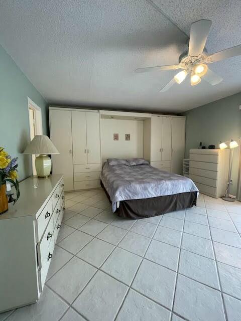 bedroom featuring ceiling fan, a textured ceiling, and light tile patterned floors